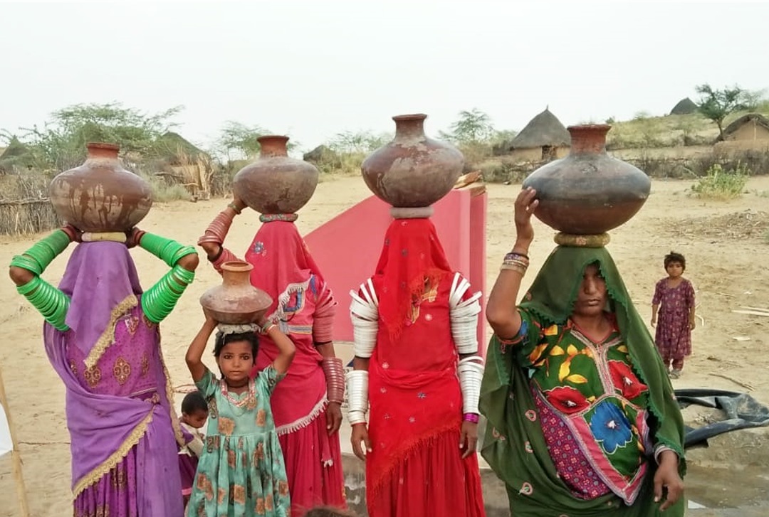 Women and children carrying water in a community served by Our Aim Foundation